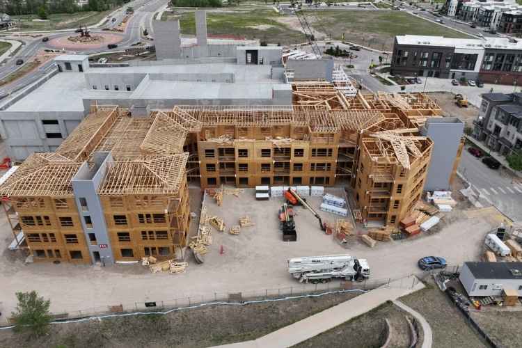 Drone aerial of a multi-family apartment building under construction with completed wood framing and concrete parking structure