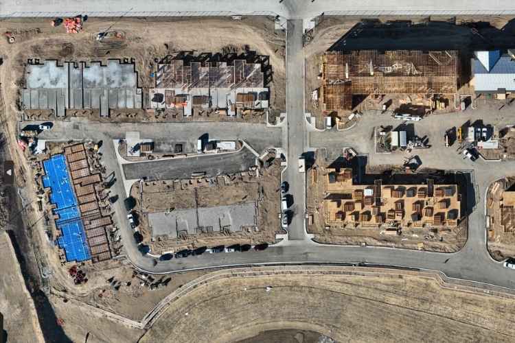 High-resolution drone aerial documenting construction progress across a multi-family residential development with framing, roofing, and site infrastructure in Arvada, Colorado